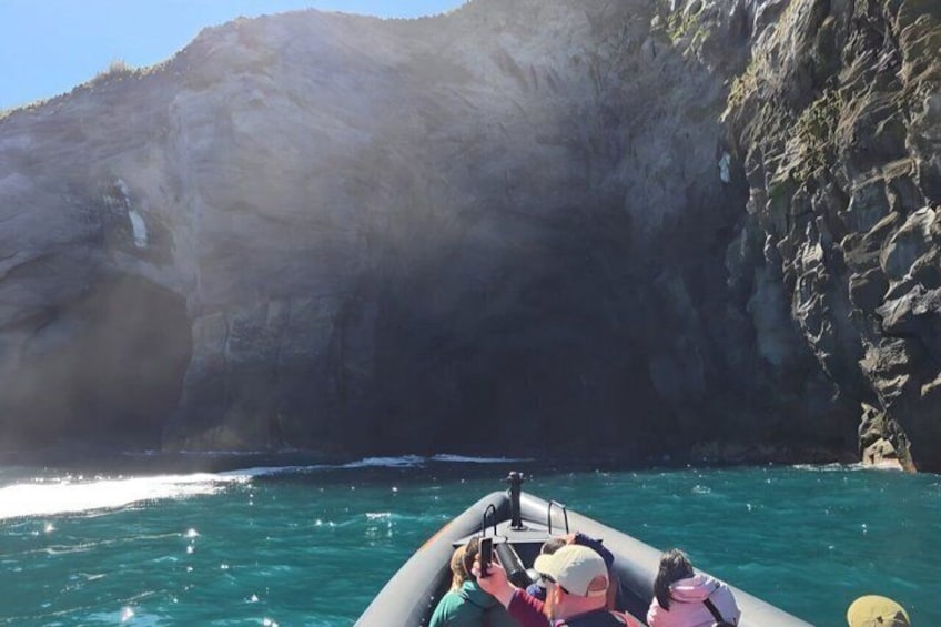 Un bote sobre aguas turquesas, con un acantilado rocoso al fondo. 2