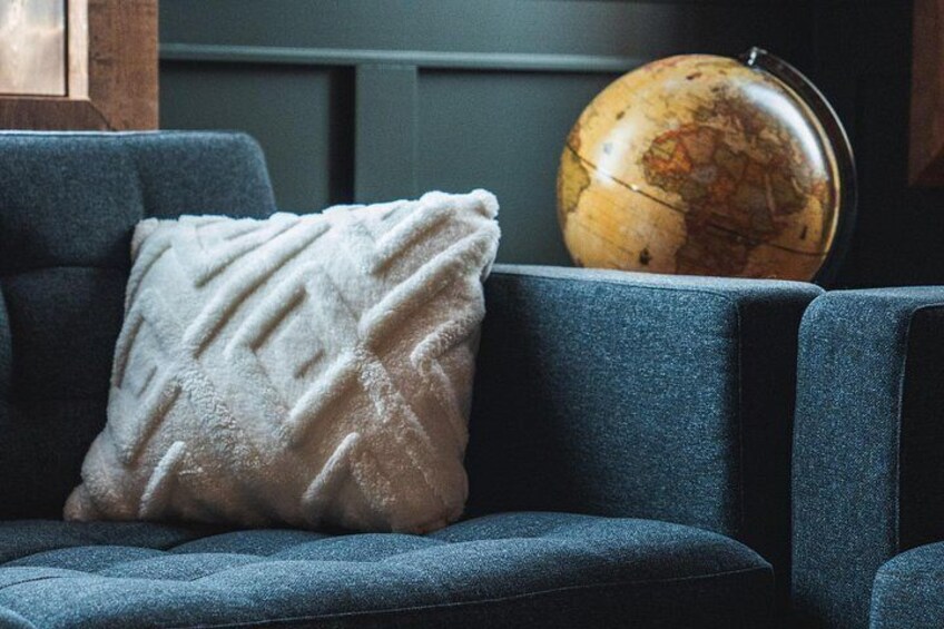A blue sofa with a textured white pillow and a globe in the background. 3