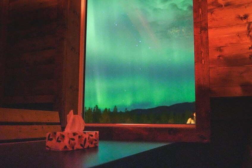 A wooden cabin with a window displaying the Northern Lights. 4