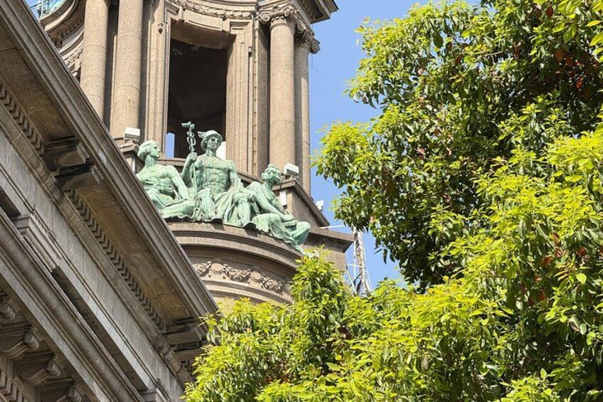 En klassisk bygning med udsmykkede søjler og en statue af en siddende figur. 3