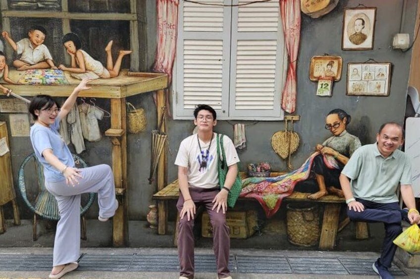 A group of people sitting and standing in a rustic outdoor setting with wooden furniture and traditional decorations. 3