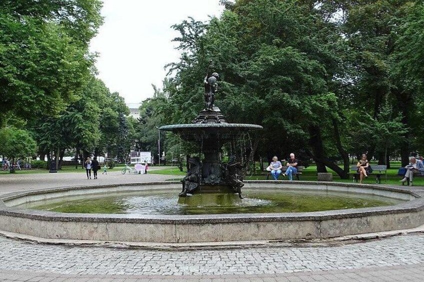 A park with a central fountain surrounded by trees and a paved walkway. 5