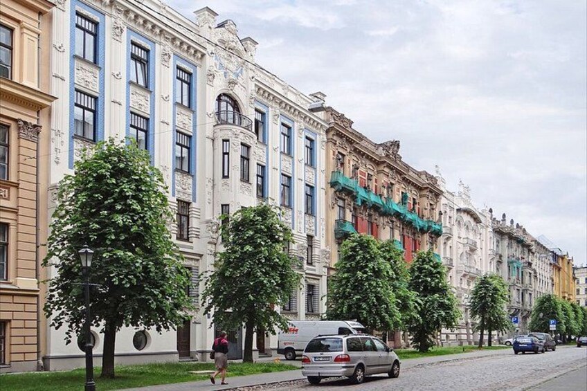 A street lined with historic buildings, trees, and parked cars. 4