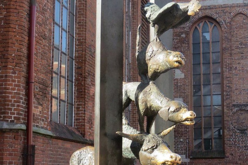 A sculpture of a horse with a rider, set against a brick building with arched windows. 3