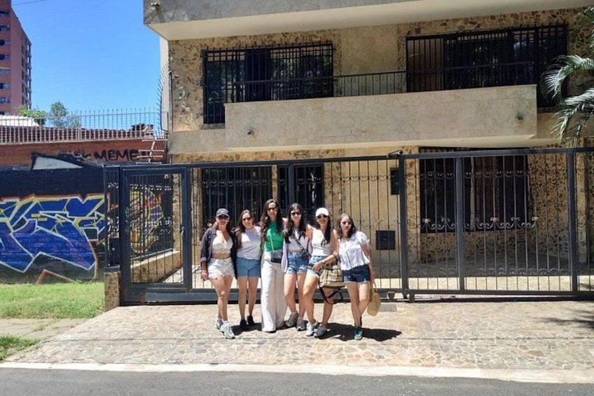 A group of people standing in front of a building with a gate and a mural. 3
