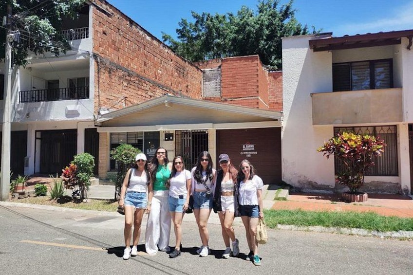 A group of people standing in front of a building with a brick facade and a white balcony. 2