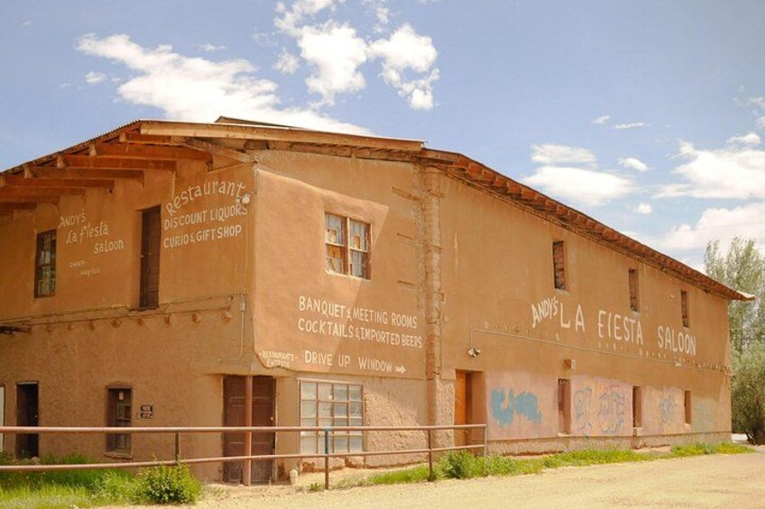 Un edificio grande y desgastado, con grafitis y letreros que anuncian un restaurante, bar y tienda de regalos. 2