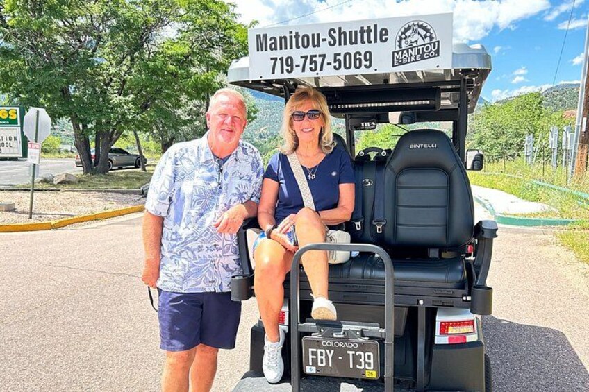 A golf cart with a sign reading 'Manitou-Shuttle 719-757-5069' and a license plate 'FBY T39'. 5