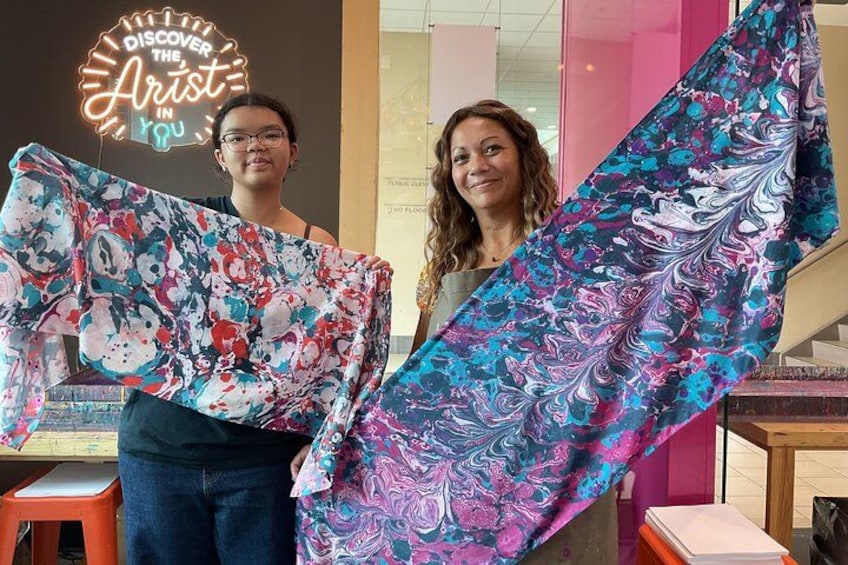 Dos personas sosteniendo un tejido colorido con estampado floral. 2
