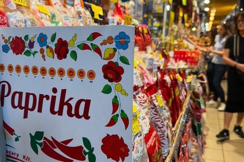 Un pasillo de tienda con un letrero que dice 'Paprika' y varios productos en las estanterías. 2