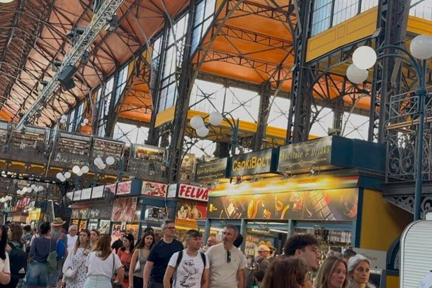 Un mercado techado concurrido, con techos altos y estructuras metálicas. 3