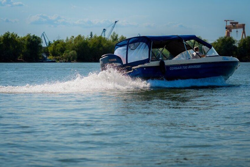 A boat speeding across calm water with industrial structures in the background. 3