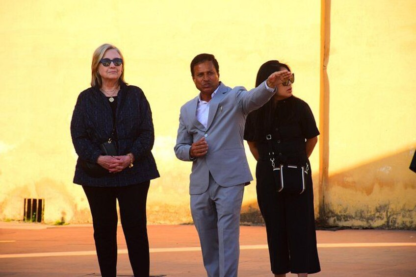Three people standing outdoors with a yellow wall in the background. 1
