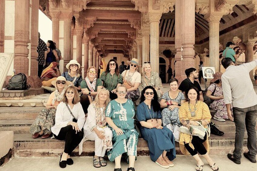 A group of people sitting on steps in front of a historical building with intricate architecture. 5