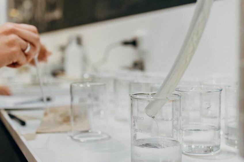 En laboratoriemiljö dÀr en person hanterar en pipett och mÀter upp vÀtskor i provrör. 3
