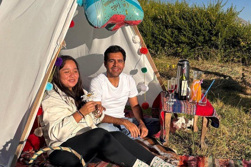 A tent with a table set up inside, featuring a bottle, glasses, and a drink. 3