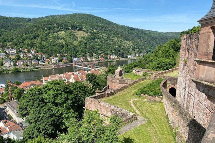 A historic fortification overlooking a river, lush greenery, and a town with red-roofed buildings. 5