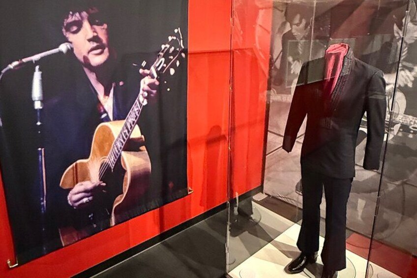 A guitar, a mannequin, and a red wall. 2