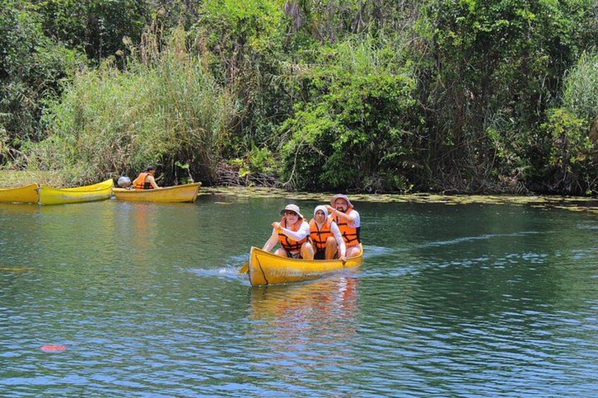Menschen in einem gelben Kanu auf einem ruhigen Fluss, umgeben von dichtem Grün. 4