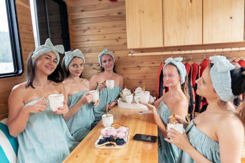 Un groupe de personnes, vêtues de robes turquoise assorties, est assis autour d’une table en bois, devant des tasses et un plateau rempli de baies. 3