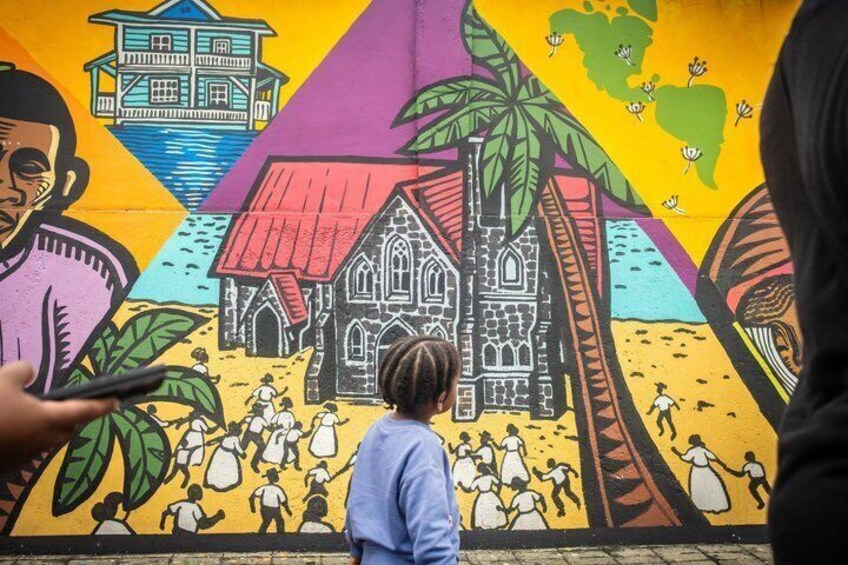 A colorful mural with a house, palm trees, and people. 5