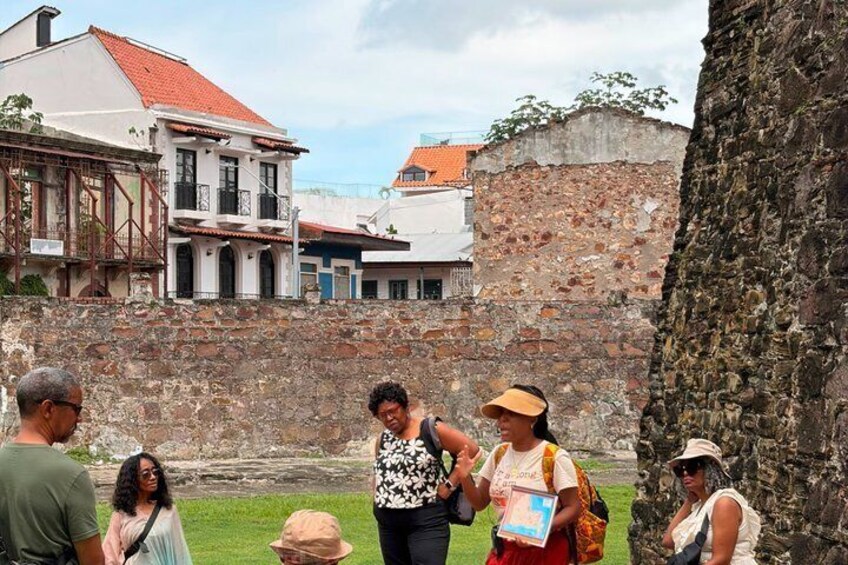 A group of people standing in a historical area with old buildings and stone walls. 4