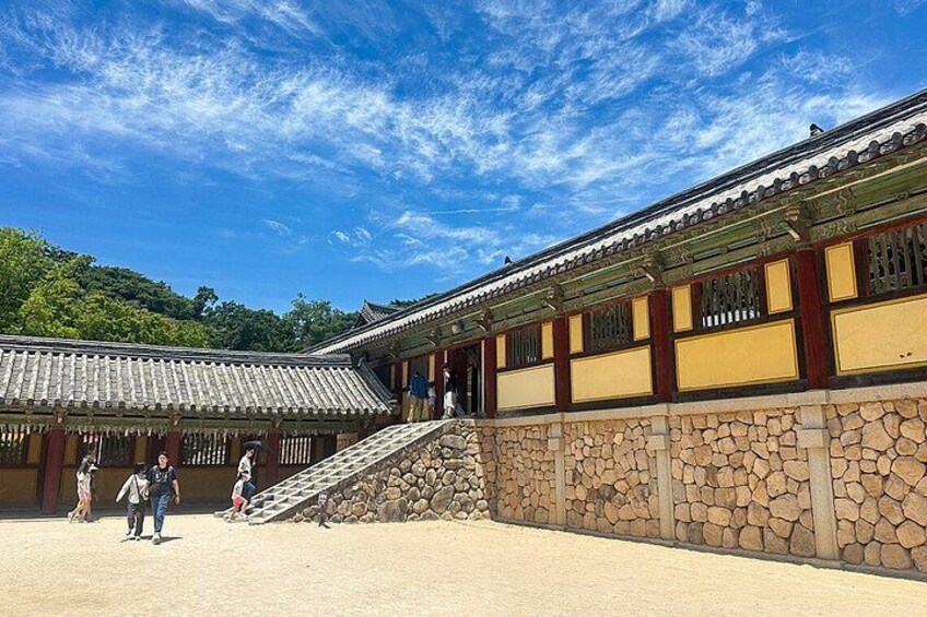 Een traditioneel Koreaans gebouw met een stenen muur, houten balken en een pannendak. 4