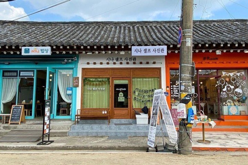 A traditional Korean storefront with a blue entrance, a wooden door, and a signboard. 5
