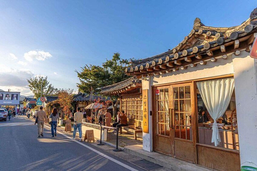 A traditional street with wooden buildings, pedestrians, and a clear sky. 5