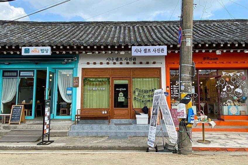 A traditional Korean storefront with a blue awning, a wooden door, and a signboard. 2