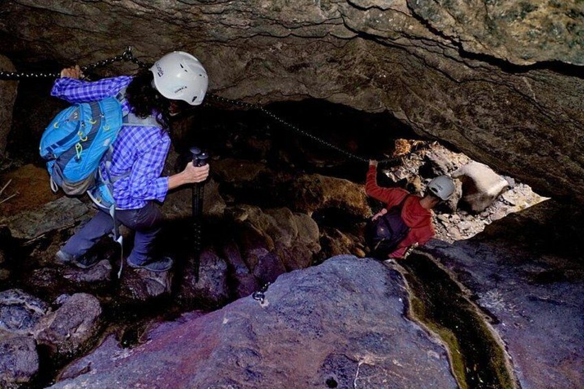 Two people hiking in a cave with rocky terrain and a stream. 4