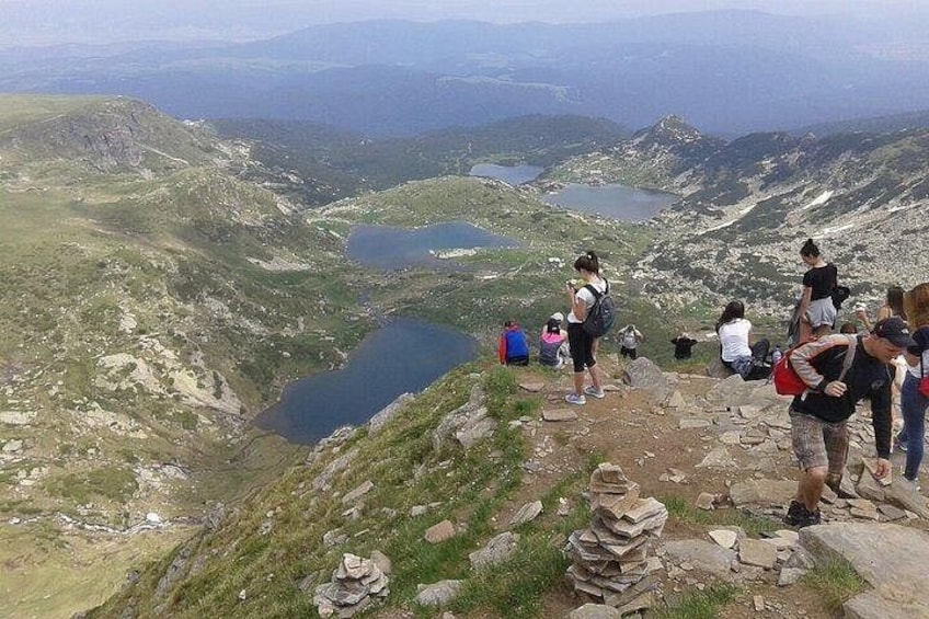 A mountainous landscape with hikers, a lake, and distant mountains. 4