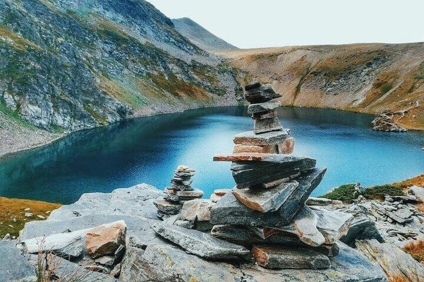 A stack of stones by a lake surrounded by mountains. 3