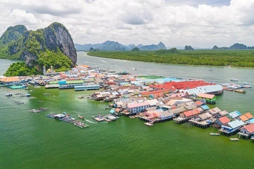 A floating village with boats and houses on stilts over water, surrounded by greenery and mountains. 5