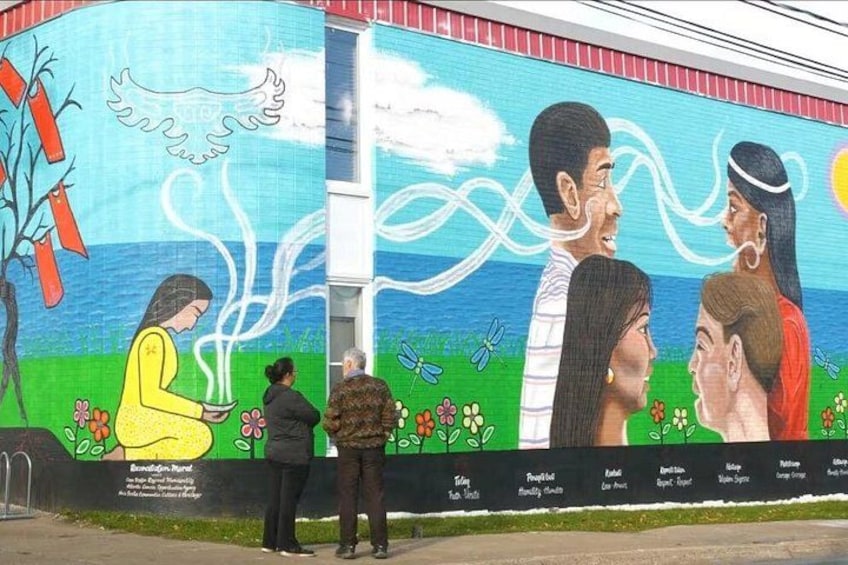 A mural with people, a tree, and flowers. 1