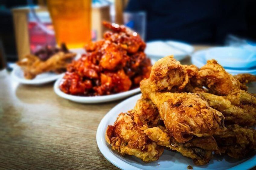 A table with plates of fried chicken and a glass of beer. 3