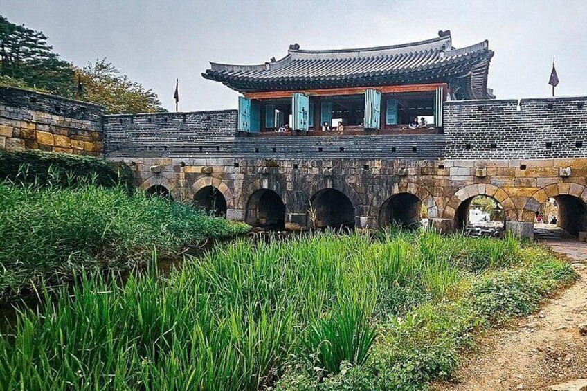 A traditional Korean building with a tiled roof and a stone bridge with arches. 2