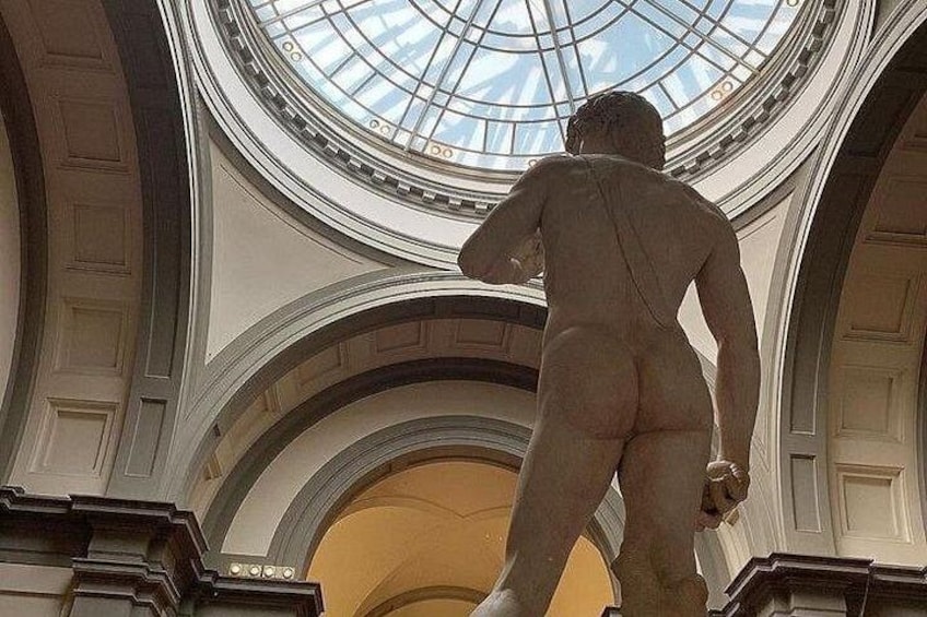 A classical statue in a grand architectural setting with a domed ceiling and arched doorways. 3