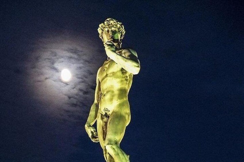 A statue illuminated against a night sky with a full moon. 5