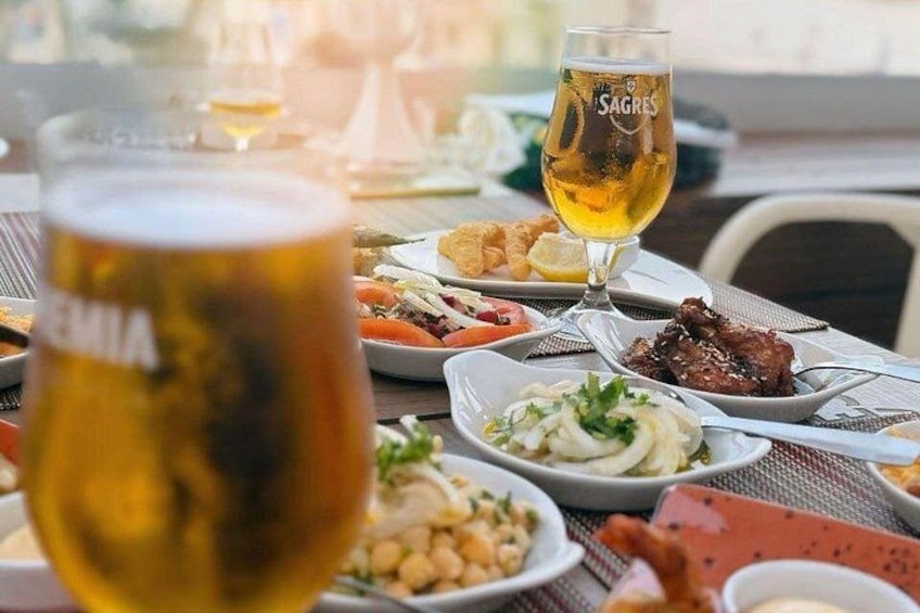 Una mesa con diferentes platos, una jarra de cerveza y una copa de vino. 4