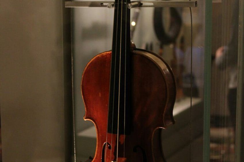 A violin inside a glass display case. 4