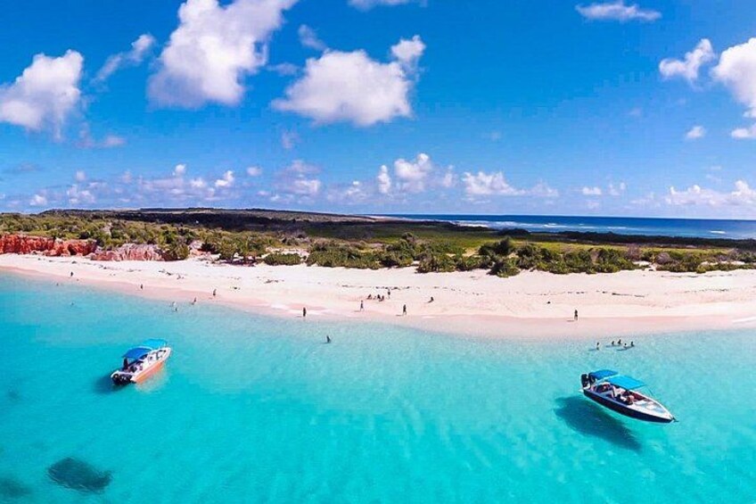 A beach with clear turquoise water, boats, and people. 2