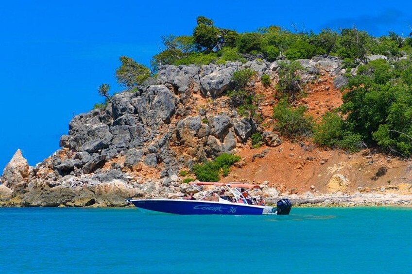 A boat on turquoise water near a rocky coastline with sparse vegetation. 3