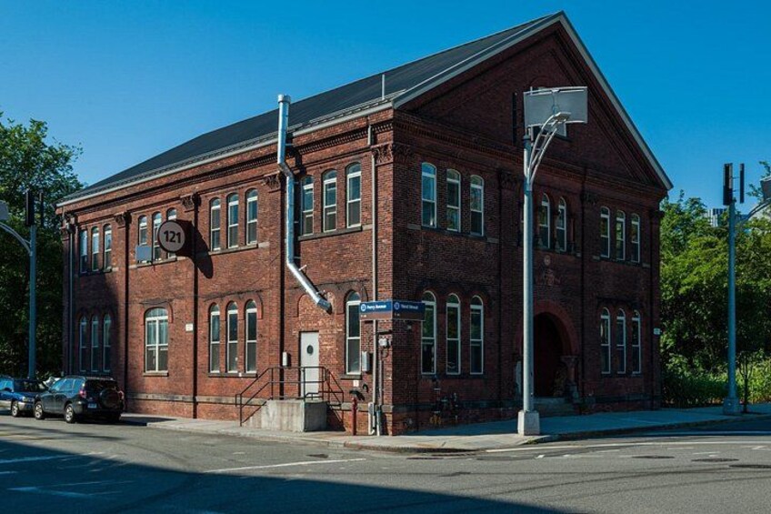 A red brick building with a basketball hoop and a street sign. 3