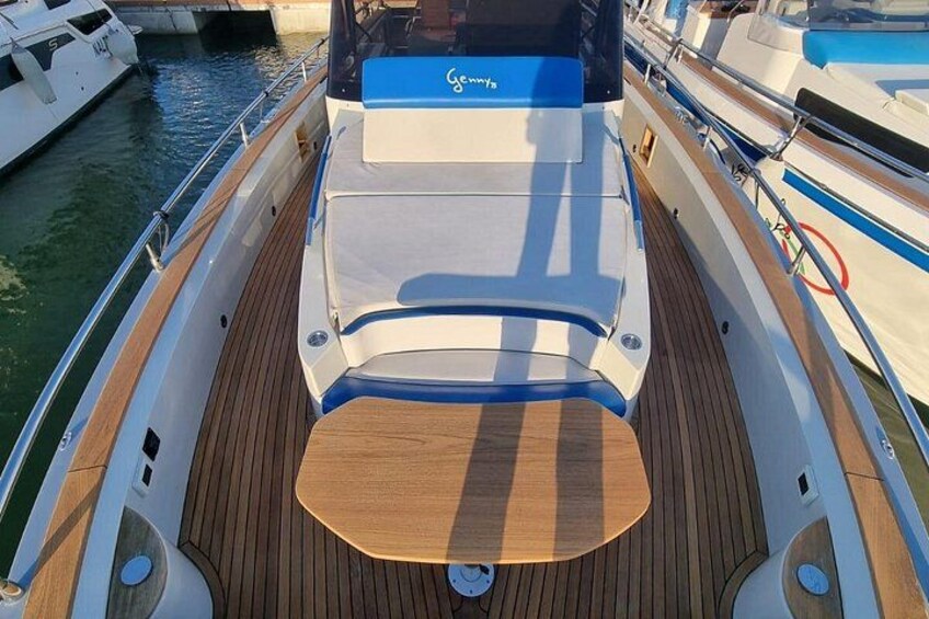 A boat's deck with a wooden floor, a central seating area, and a railing. 4