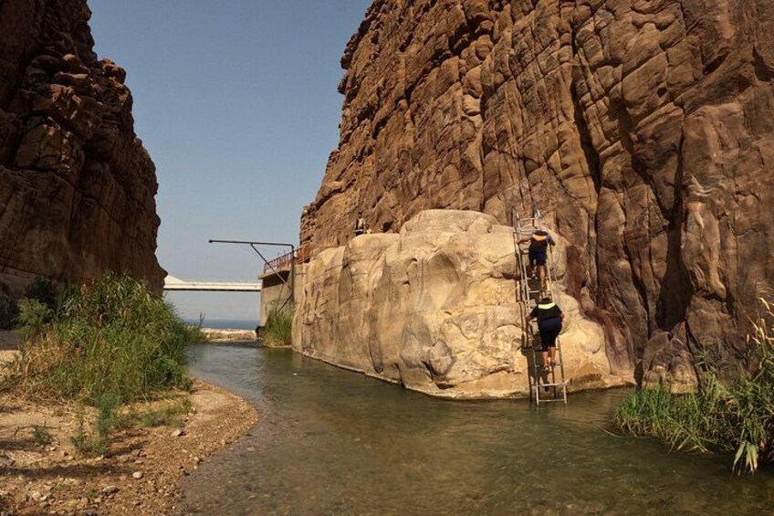 A canyon with a river, a bridge, and a person climbing a rock wall. 2