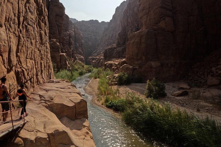 A canyon with a river, rocky cliffs, and a wooden viewing platform. 3