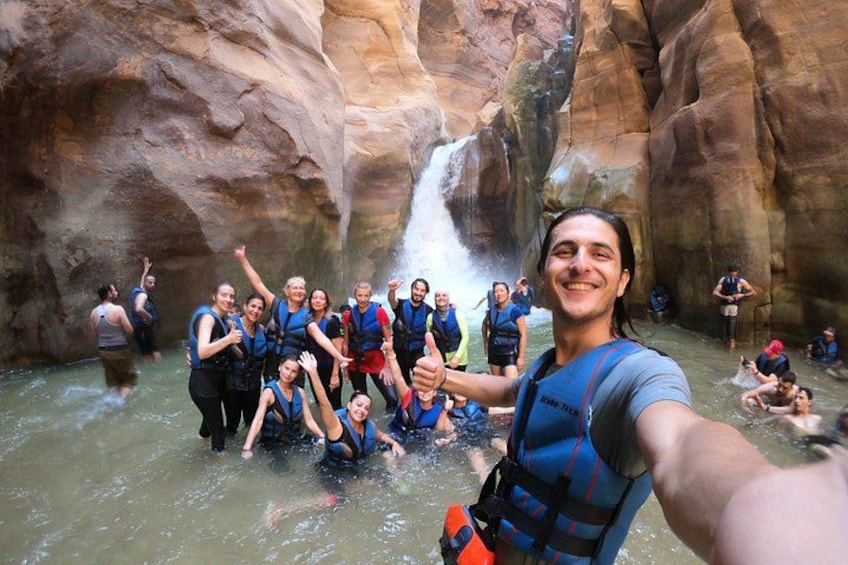 A group of people in a canyon with a waterfall. 1