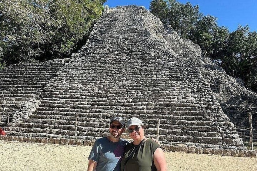 A large stone pyramid with multiple tiers and a person standing in front of it. 4