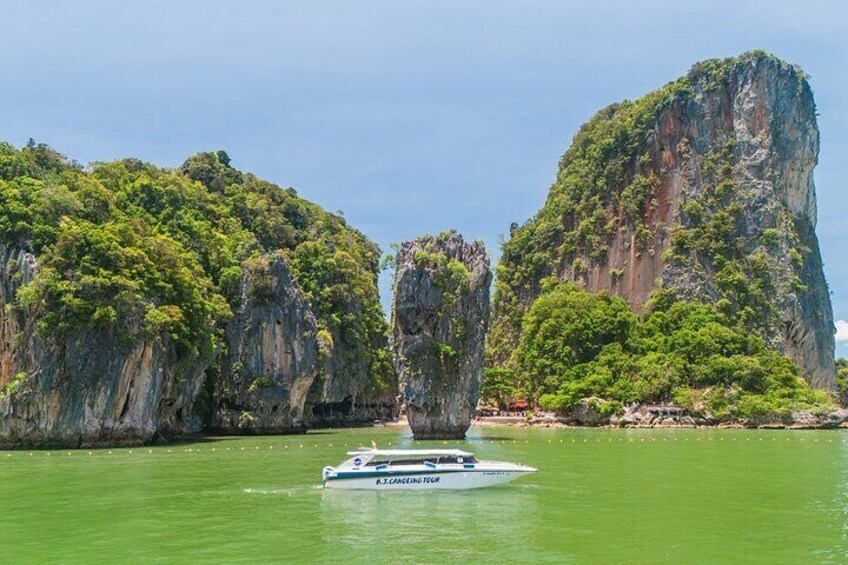 A boat named "R.J. Canning" on greenish water with two large limestone cliffs and dense green vegetation in the background. 1
